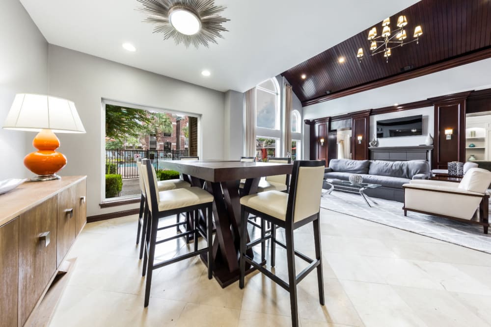 Community clubhouse dining table and chairs with view of pool deck at Marquis on Park Row in Houston, Texas