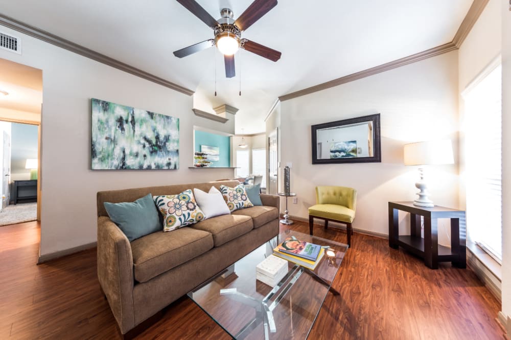 Bright and cheerful living room with wood flooring and ceiling fan at Marquis on Park Row in Houston, Texas