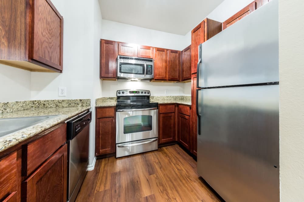 Entrance to modern kitchen with stainless steel appliances and granite counters at Marquis at Barton Trails in Austin, Texas