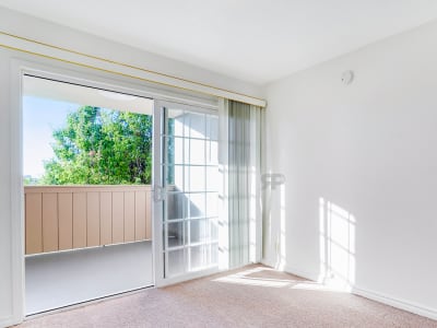 Brightly lit living room with balcony access at St. Moritz Garden Apartments in San Leandro, California