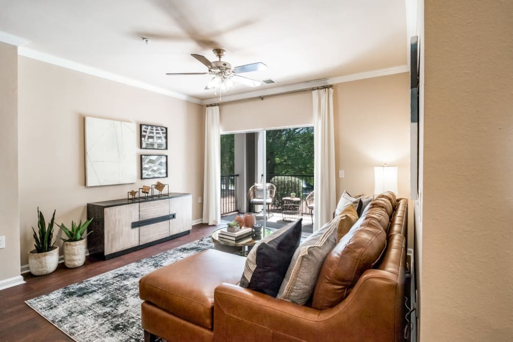 Sleek and modern style living room with private patio and wood flooring at Marquis at Carmel Commons in Charlotte, North Carolina