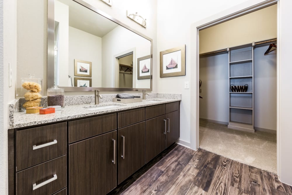 Large bathroom with double sinks and walkway to large walk-in closet at Marq Uptown in Austin, Texas