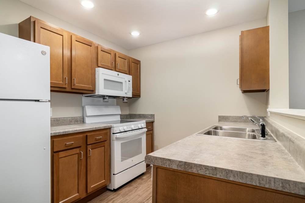 Bright kitchen featuring stainless steel appliances, granite countertops, and wood-style flooring at Haven Crossing in Walton, Kentucky