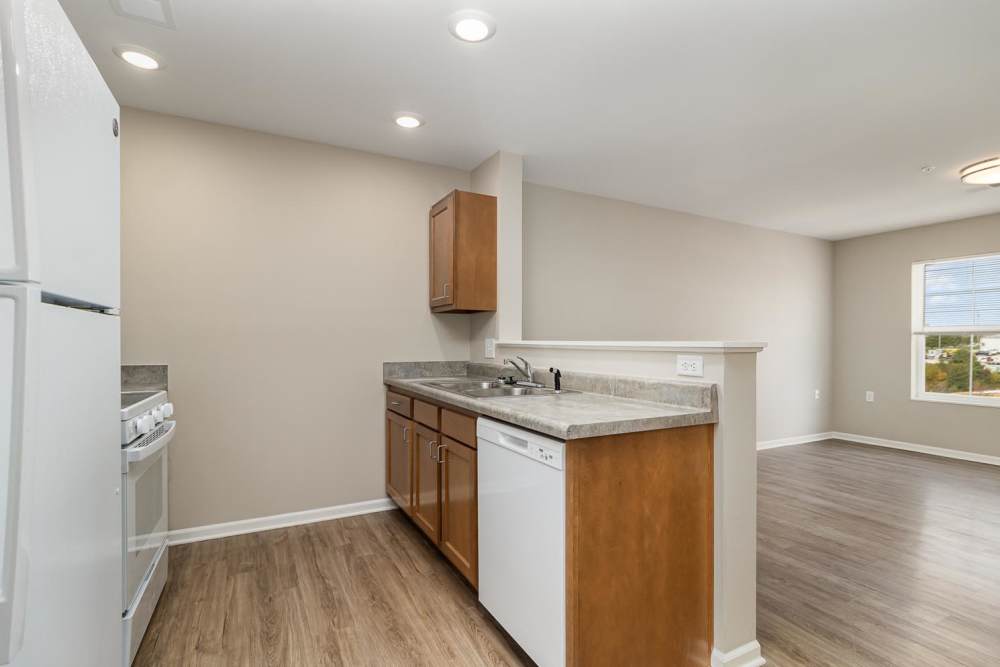 Modern kitchen with stainless steel appliances, granite countertops, and wood-style flooring in open layout at Haven Crossing in Walton, Kentucky