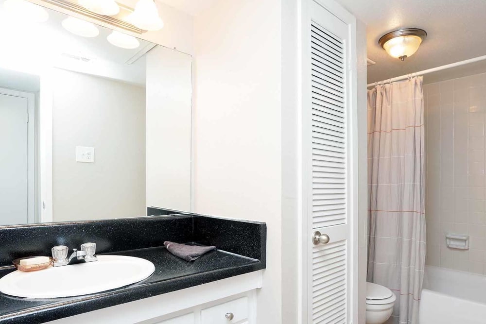 Black granite style countertop in this well-lit bathroom at Brittany Place Apartments in Houston, Texas