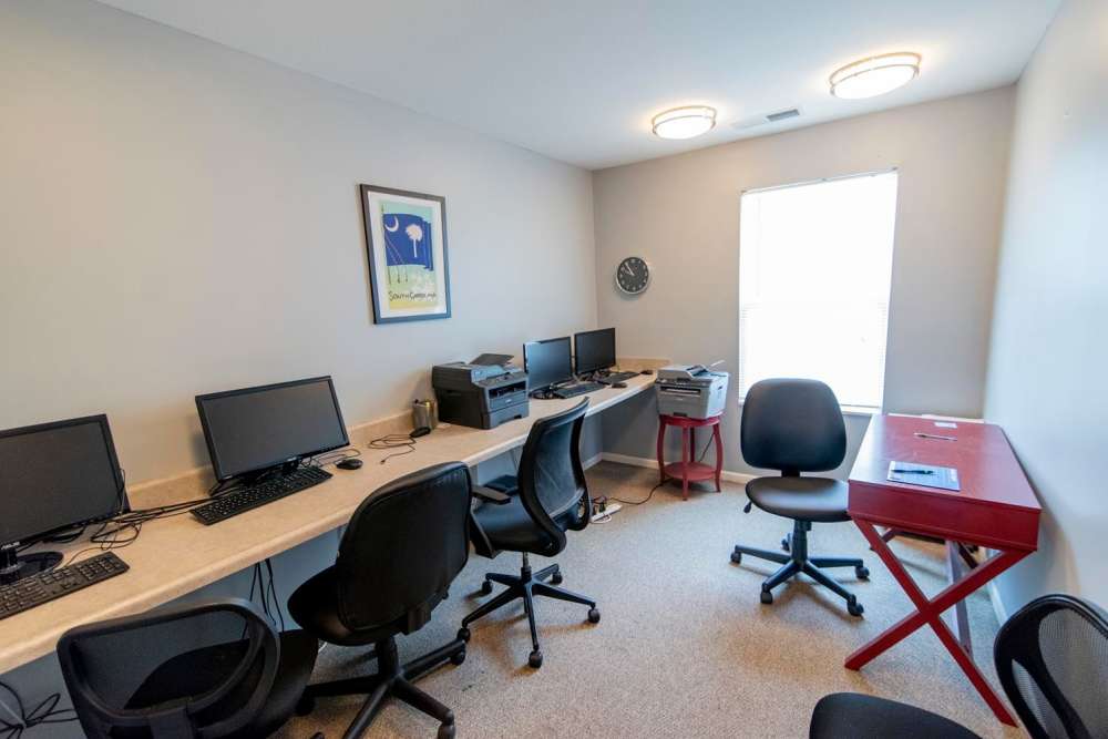 Modern workspace with multiple computers, ergonomic chairs, natural light, and vibrant wall art at Butler Crossing II in Kingstree, South Carolina