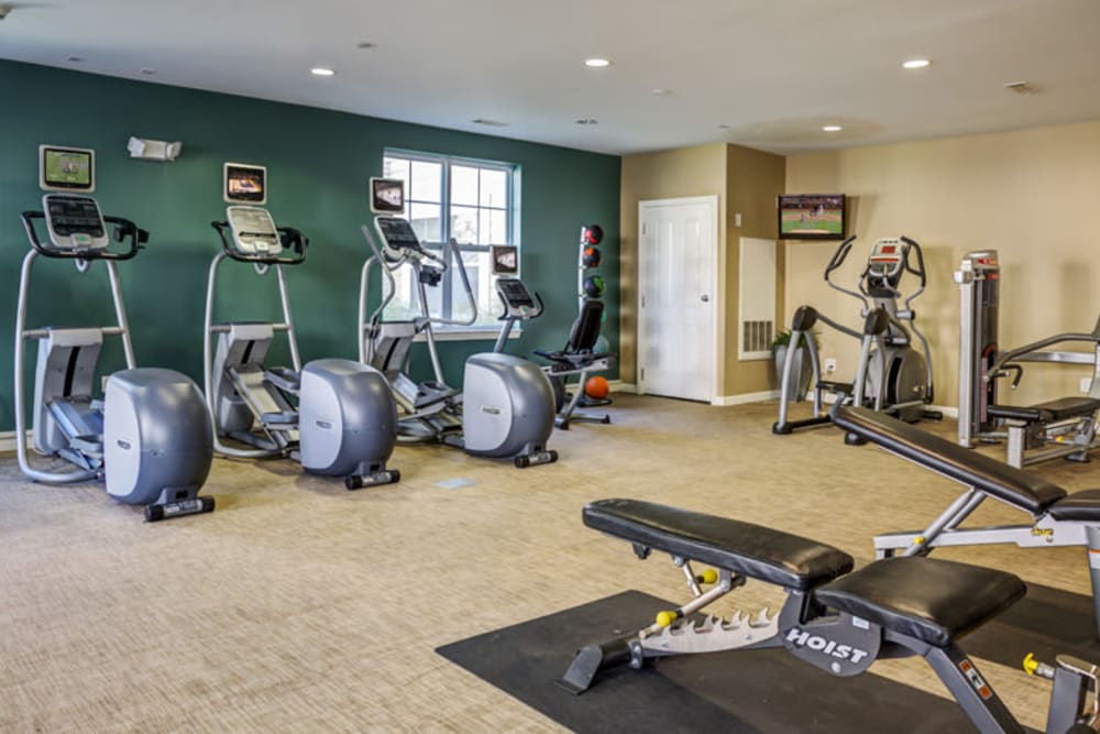 A gym area with multiple biking machines and lifting benches at Parkside Commons in Chelsea, Massachusetts