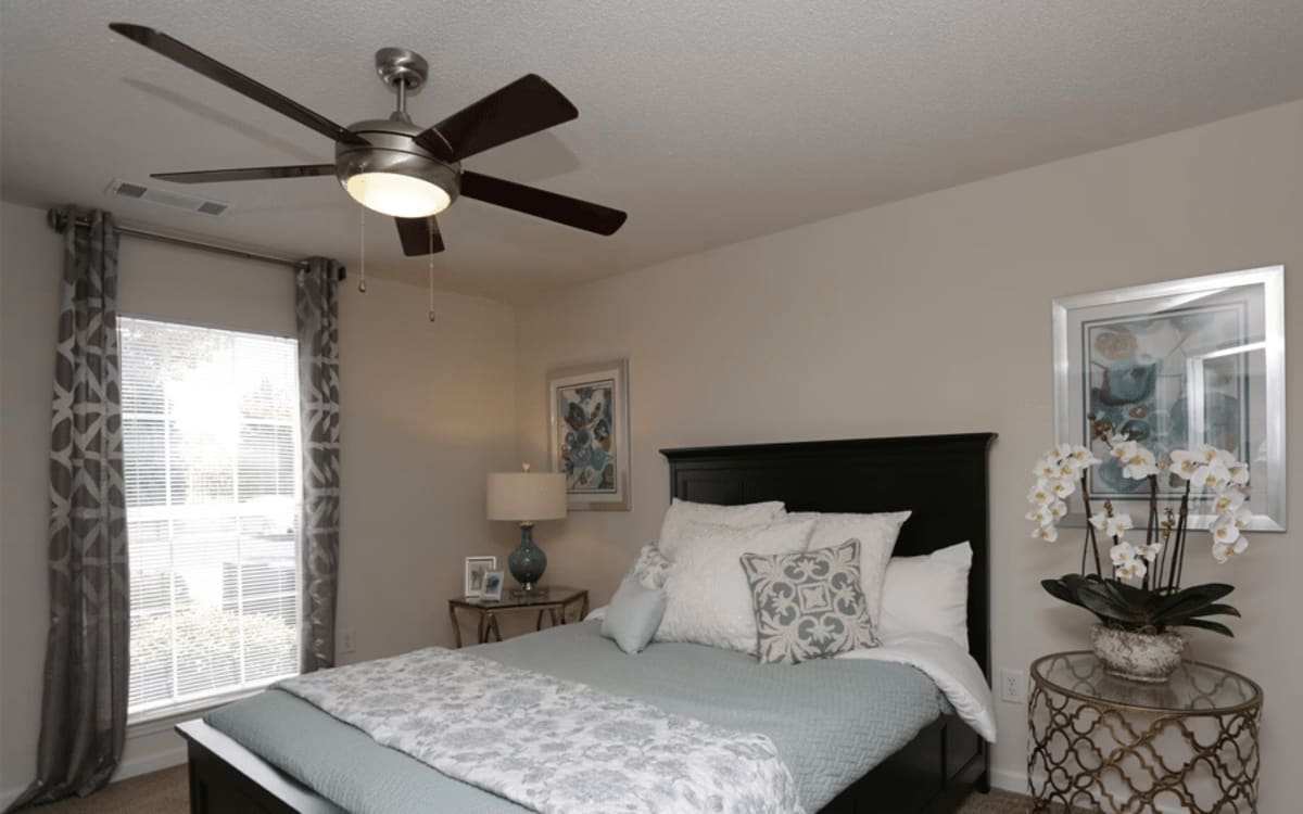 Bedroom with a large bed and ceiling fan at Arbors at Fairview Apartments in Simpsonville, South Carolina