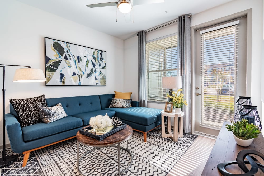 Modern apartment living room with coffee table, blue sofa, and large water color art on the wall at Vue on Lake Monroe in Sanford, Florida