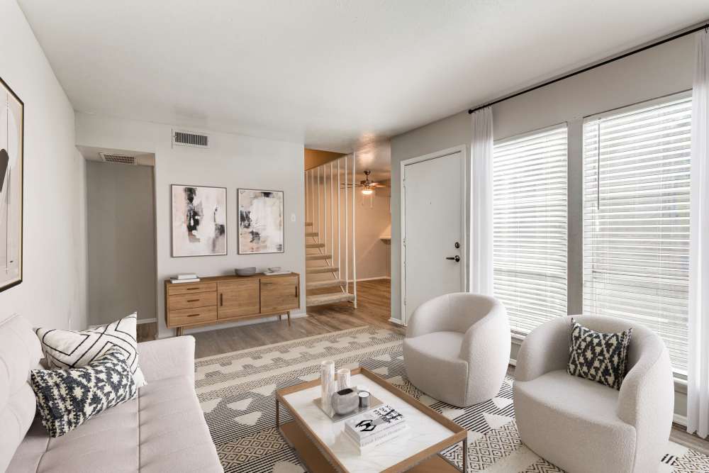 Modern living room with large couch, chairs and wood-style flooring at Tribecca Pointe Apartments in Hurst, Texas