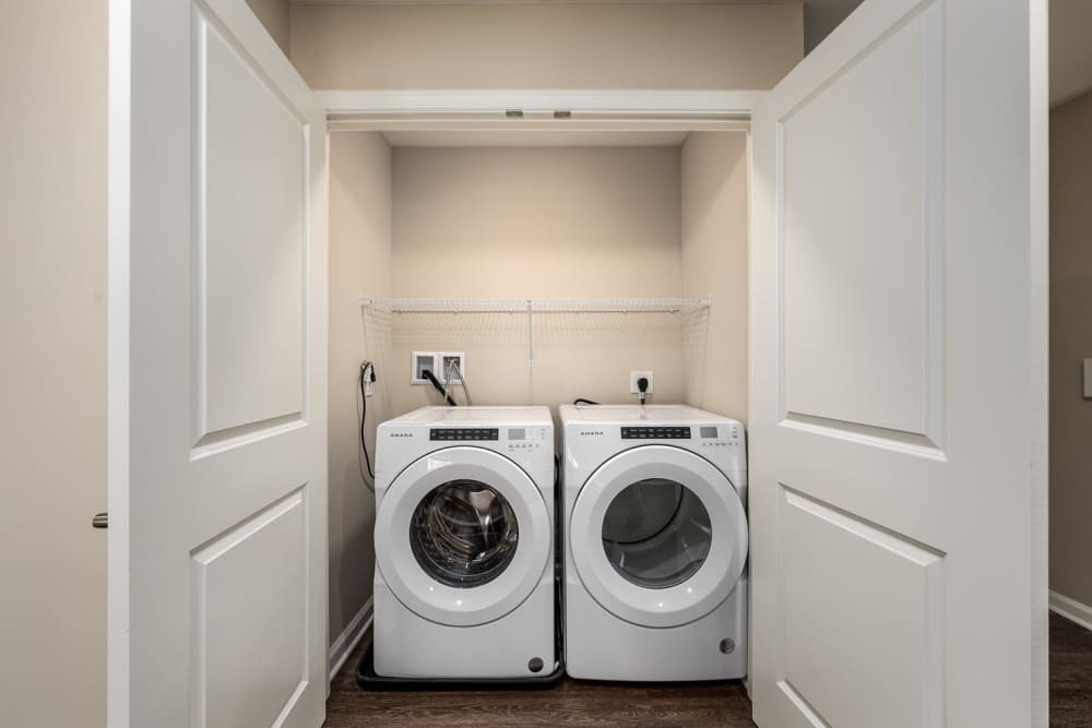 Washer and dryer in a laundry closet with wood-style flooring and white doors at Owens Greene in Wheeling, West Virginia