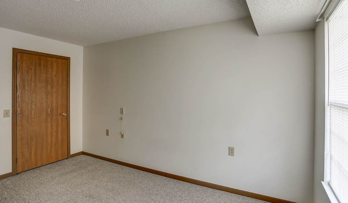 Carpeted floor with beige walls and wooden door at Laurelhurst in Clyde, Ohio