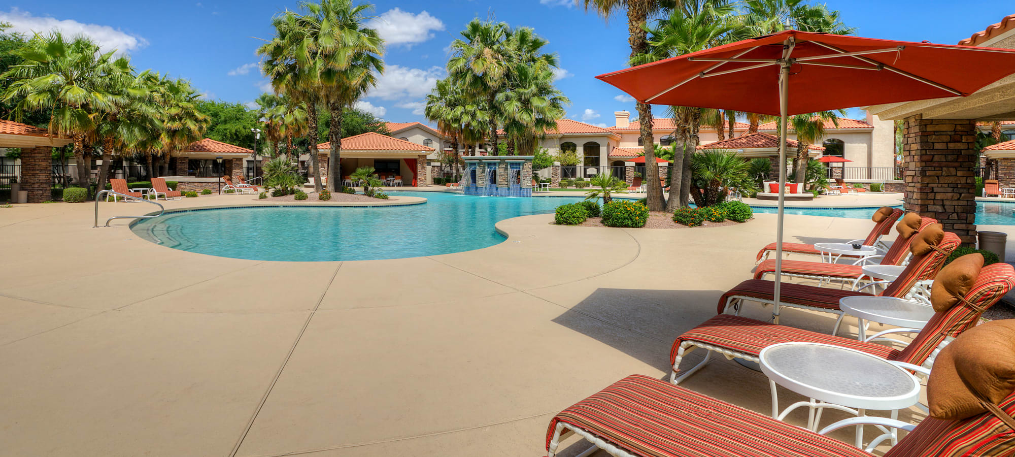 Chaise lounge chairs and umbrellas near the pool at San Palacio in Chandler, Arizona