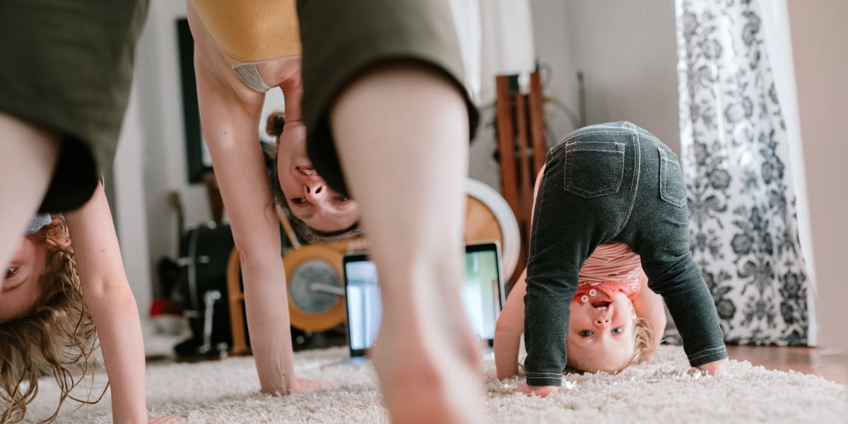 Resident doing yoga with her kids in living room at Marquis at Bellaire Ranch in Fort Worth, Texas