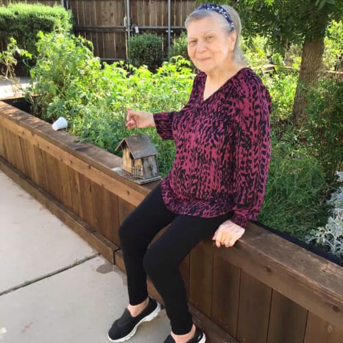 Resident sitting outside holding a birdhouse at Oxford Glen Memory Care at Grand Prairie in Grand Prairie, Texas