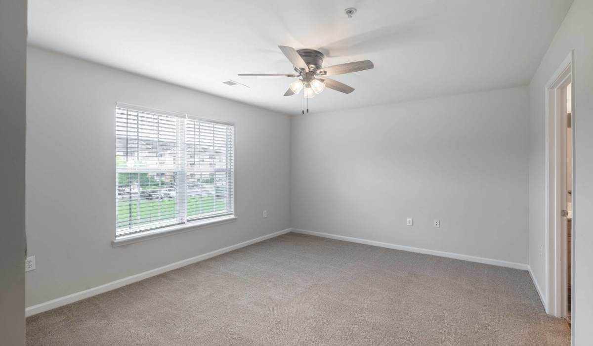 Unfurnished bedroom with ceiling fan and large window at Palisades at Carters Mill in Sumter, South Carolina