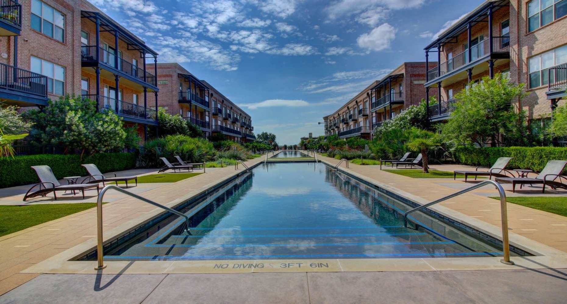 Resort-style large swimming pool, lounge chairs at Flatiron District at Austin Ranch in The Colony, Texas