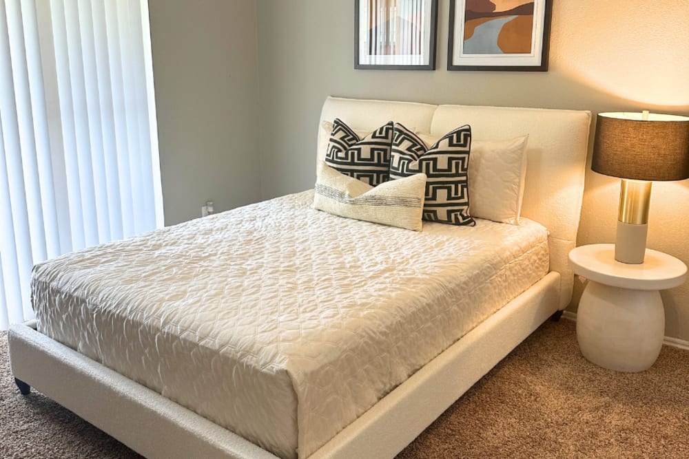 A comfy bed in a bedroom of the apartment at Walnut Ridge in Arlington, Texas