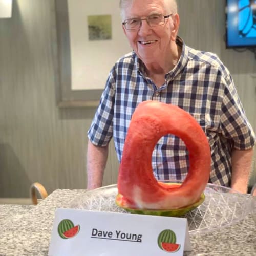A resident standing next to his watermelon carving at Oxford Villa Active Senior Apartments in Wichita, Kansas