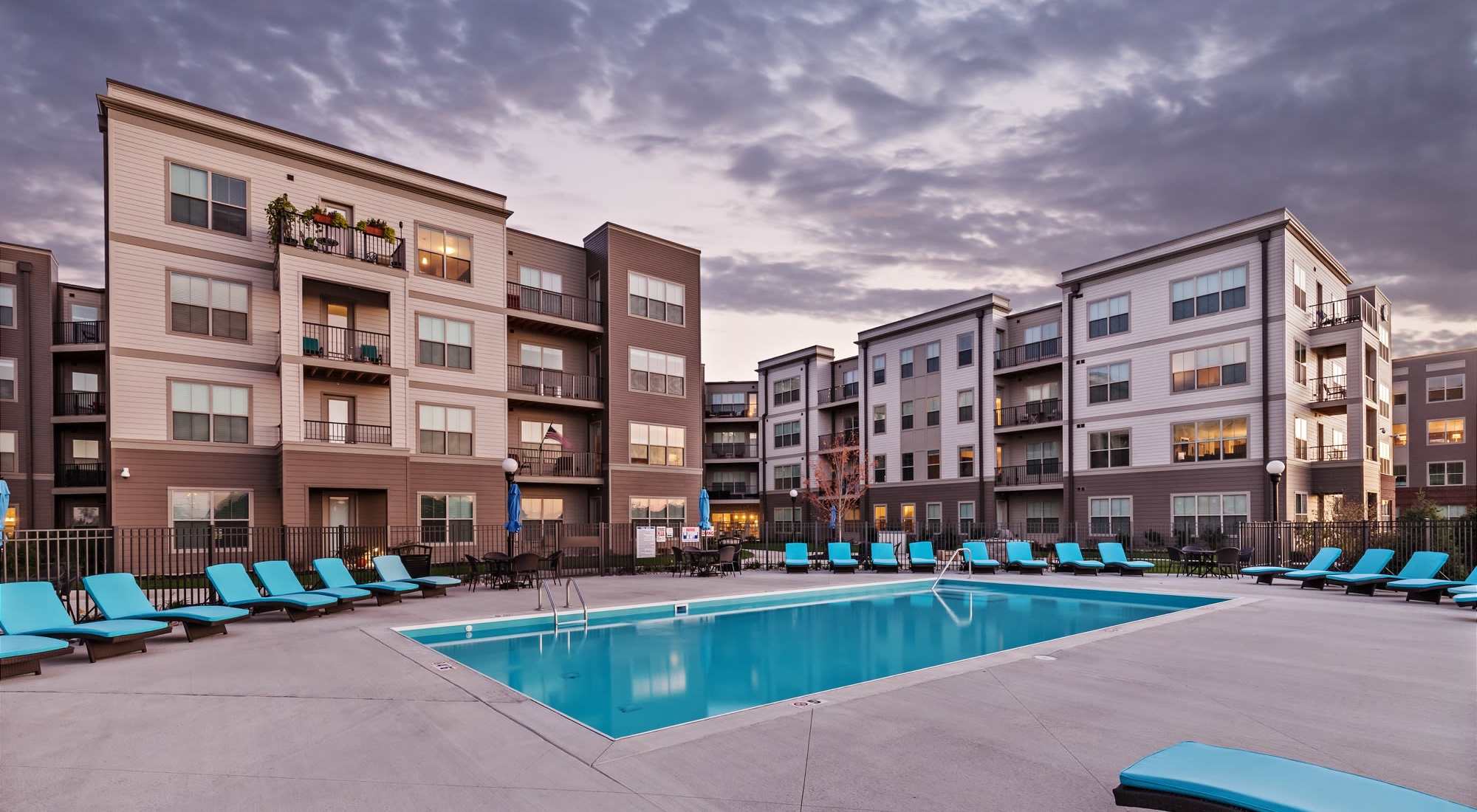 Resort-style pool surrounded by lounge chairs and modern apartment buildings with balconies at Water Street Apartments in Dayton, Ohio 