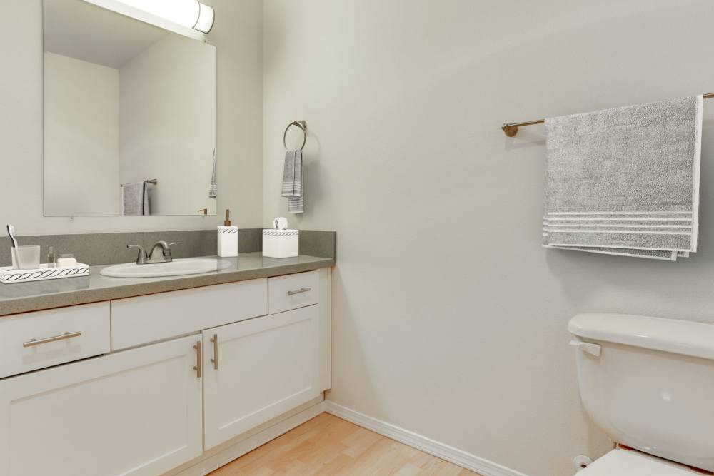 Renovated bathroom with white cabinets and a bathtub at The Addison Apartments in Vancouver, Washington
