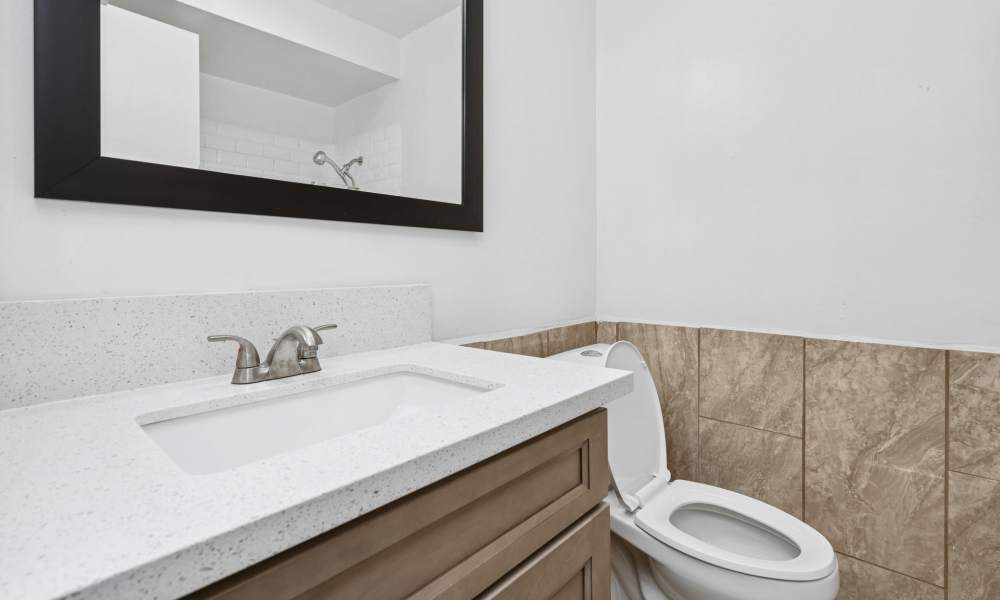 Bathroom with framed mirror, sink, commode and storage space at Newland Garden Apartments in Garden Grove, California