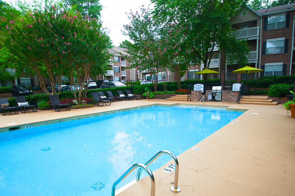 Sparkling swimming pool with a poolside grilling station and plenty of lounge chairs to soak up the sun at Castlegate Collier Hills in Atlanta, Georgia