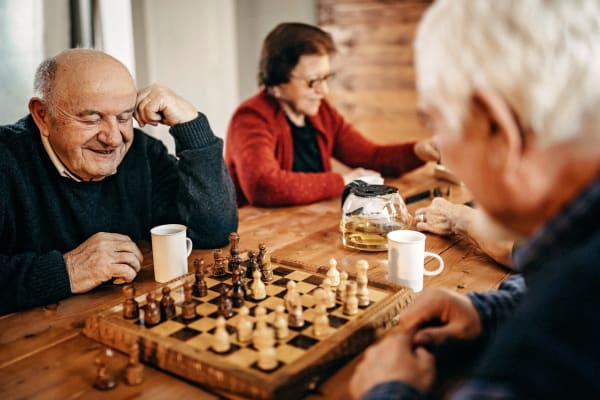 An elderly man playing chess with his friend at Regency Palms Palmdale in Palmdale, California