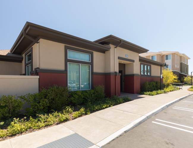 Contemporary building with vibrant landscaping and large windows at Antioch Family & Senior Apartments in Antioch, California