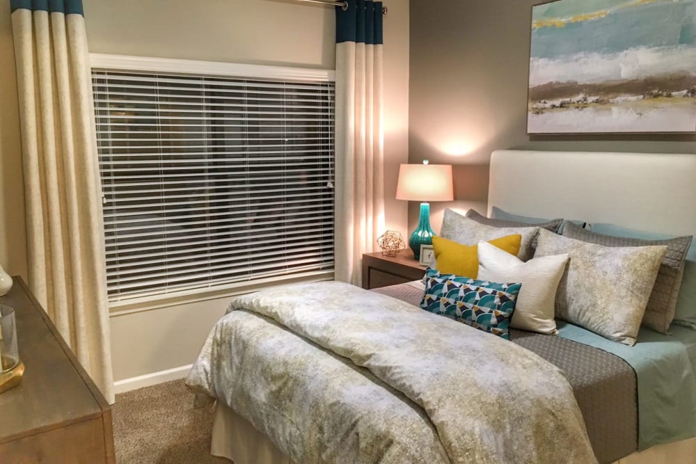 Model home's primary bedroom with an accent wall and draped bay windows at Cahaba Grandview in Birmingham, Alabama