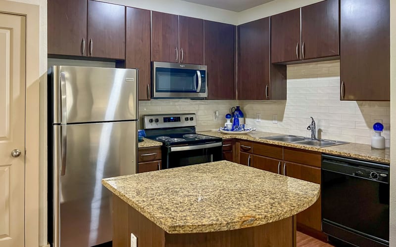 Renovated kitchen with stainless steel appliances and brown cabinets at Broadstone Grand Avenue in Pflugerville, Texas