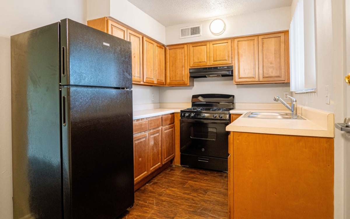 Kitchen with wooden cabinets and appliances at Caroline Arms in Jacksonville, Florida