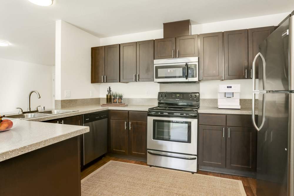 Renovated kitchen with brown cabinets and stainless steel appliances at The Addison Apartments in Vancouver, Washington