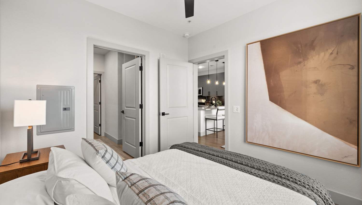 Model apartment bedroom with cozy bed and side table at The Lock at Flatirons in Broomfield, Colorado