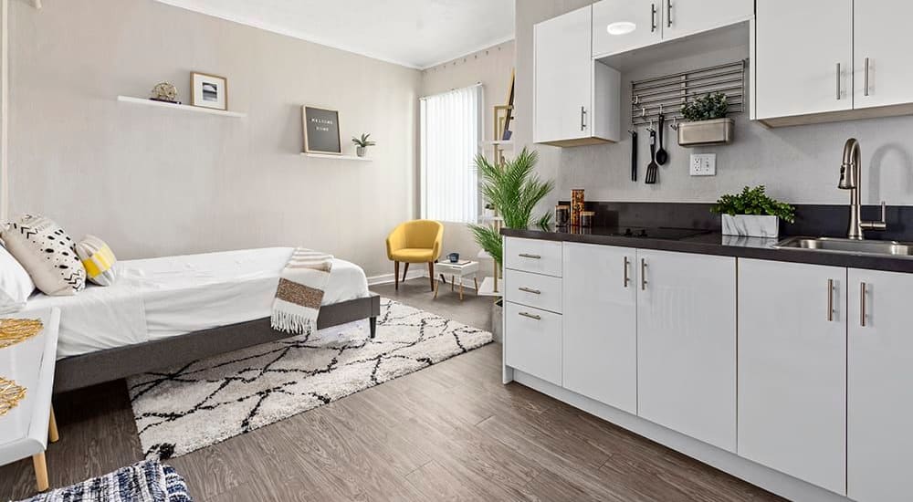 Model studio apartment with white kitchen cabinetry and wood-style flooring at Langdon Park at Hollywood Studios in Los Angeles, California