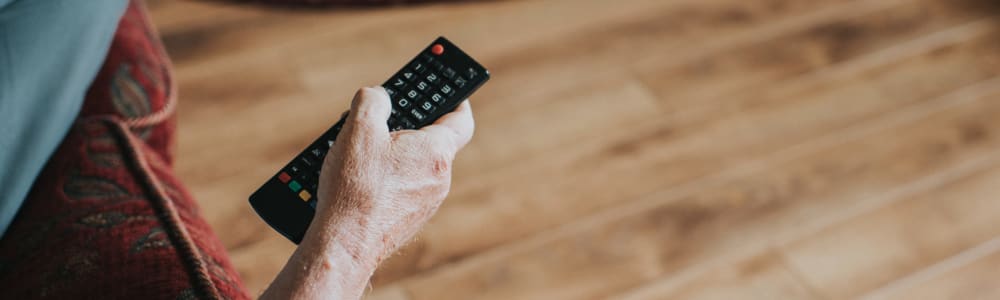 Resident laying on their couch channel-surfing with a remote in their hand at Fair Oaks Health Care Center in Crystal Lake, Illinois