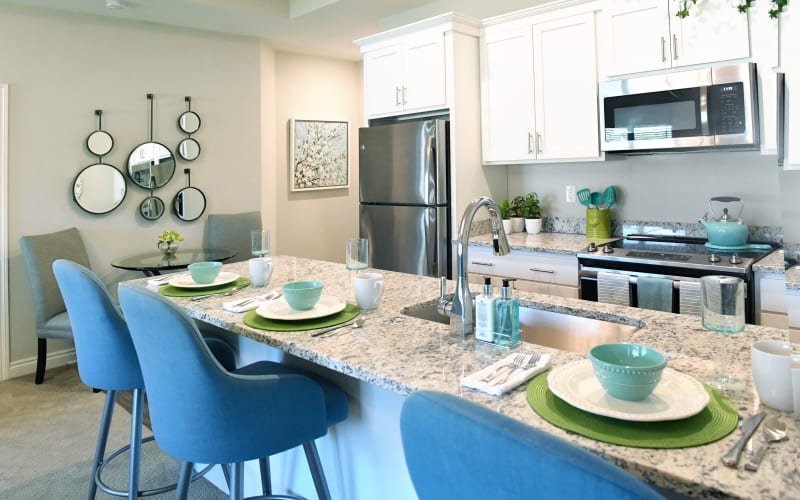 Kitchen in a memory care residence with stone counter tops ant stainless steel appliances at Blossom Collection in Rochester, Michigan