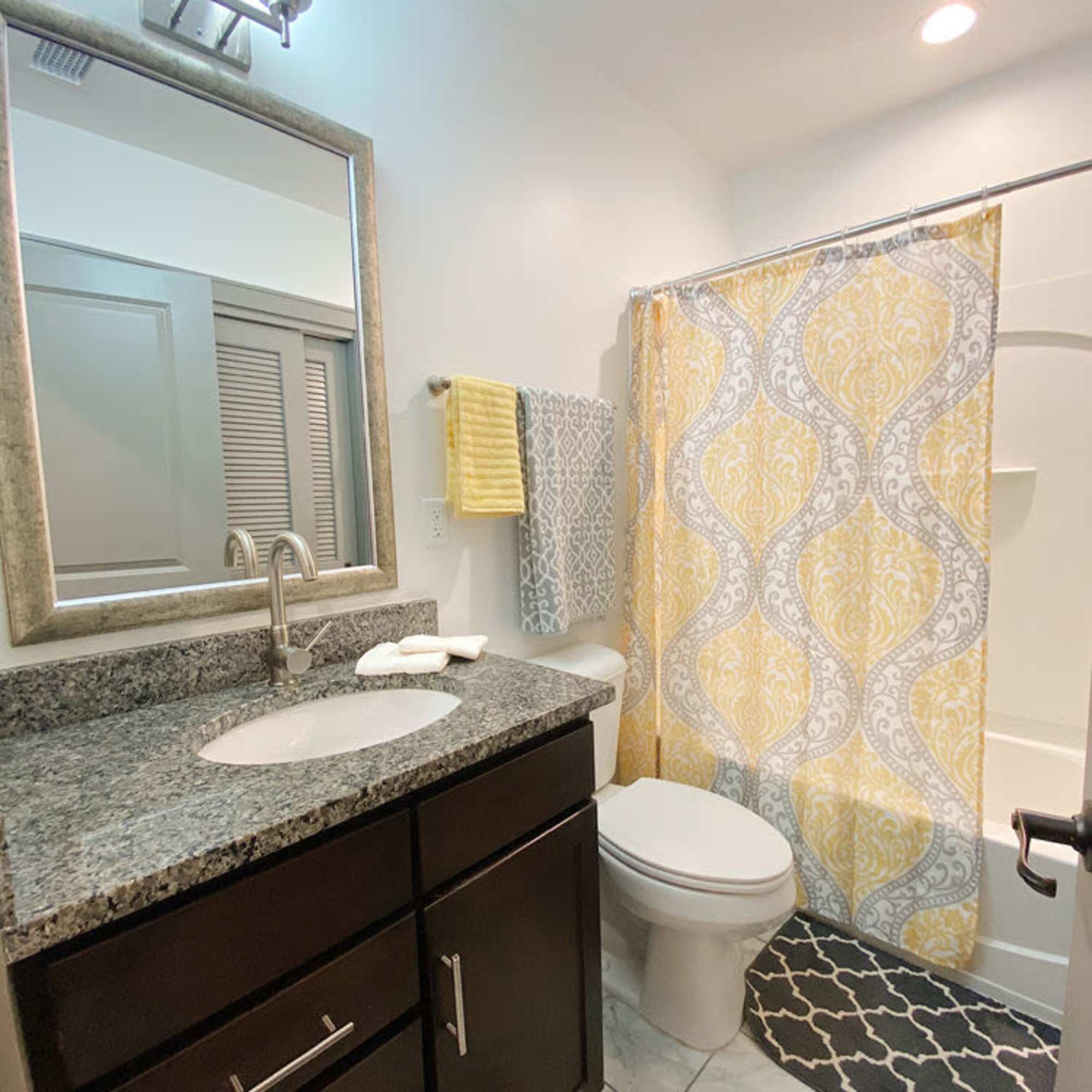 Bright bathtoom with vanity light, mirror, sink, commode and bathtub at The Atlas in Columbus, Ohio