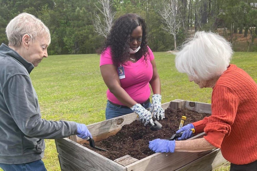 Residents gardening with their caregiver at Carolina Gardens at Conway in Conway, South Carolina