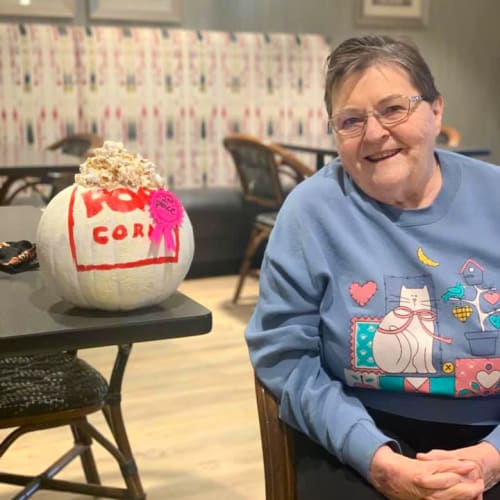 Resident sitting next to a painted pumpkin at Oxford Villa Active Senior Apartments in Wichita, Kansas