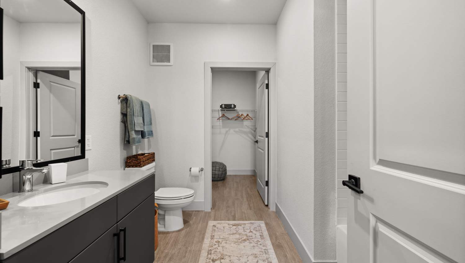 Well-lit bathroom with standard bath tub, vanity and commode at The Lock at Flatirons in Broomfield, Colorado