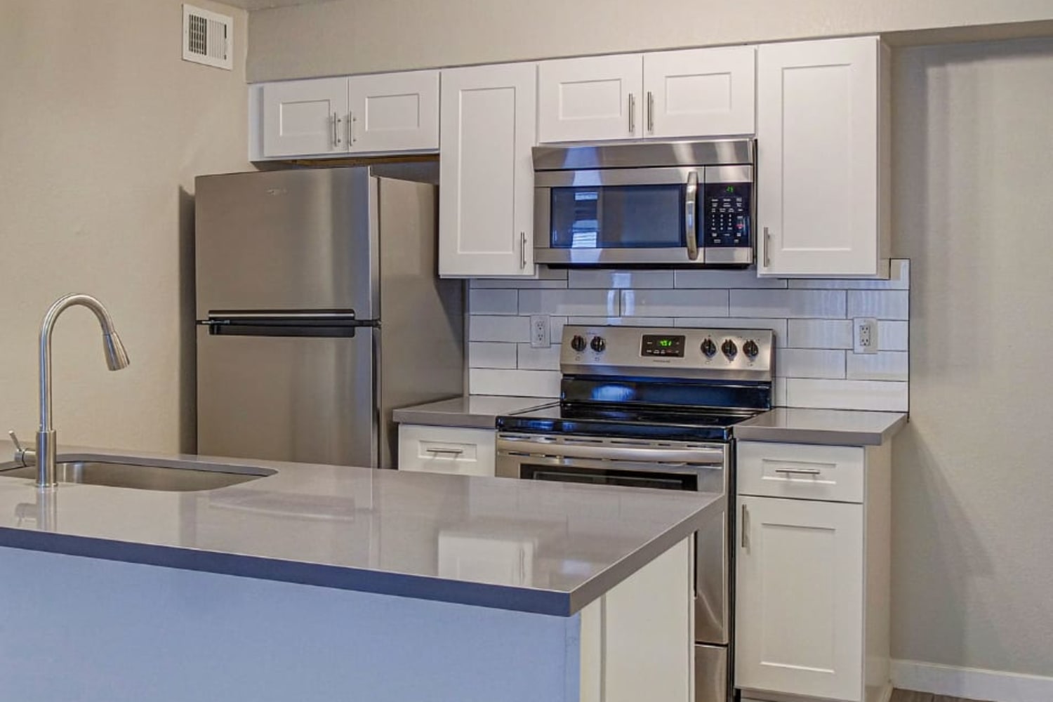 White cupboards and stainless-steel appliances in an apartment kitchen at Station 21 Apartments in Mesa, Arizona