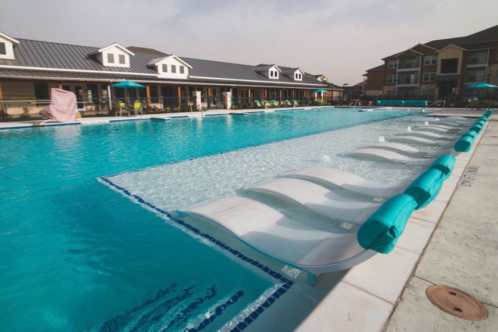 Resort style lounge chairs in the pool at Biltmore at the Park in Pflugerville, Texas