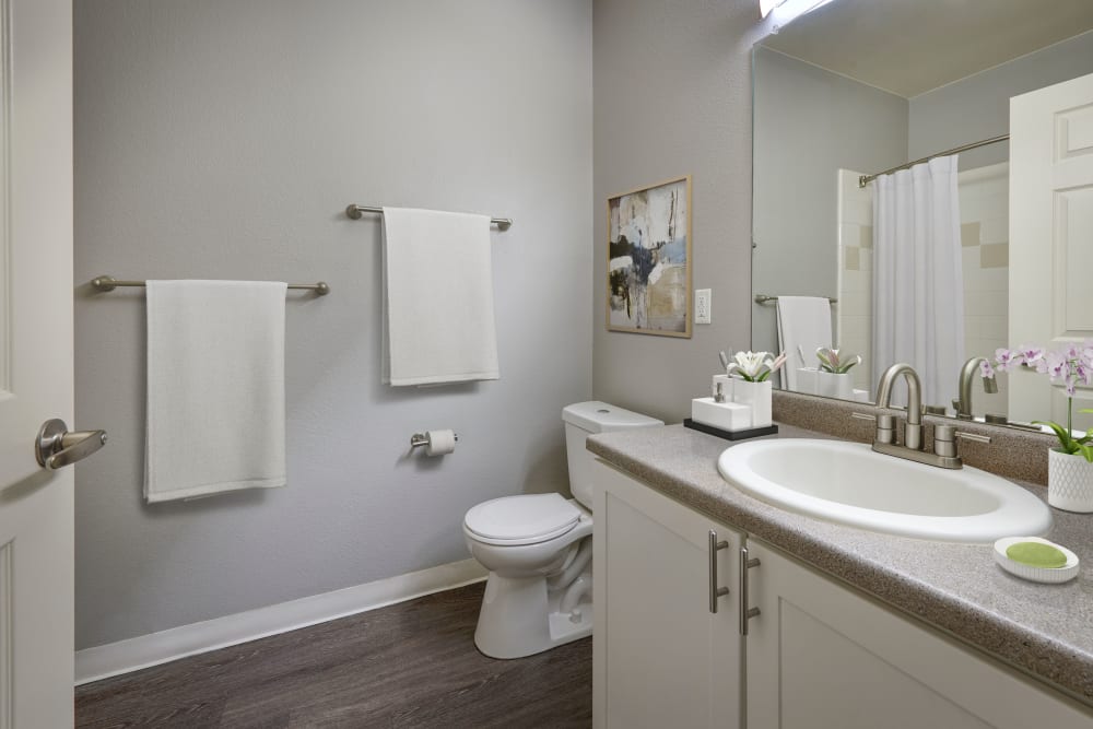 A model bathroom with white cabinets and updated lighting at Westridge Apartments in Aurora, Colorado