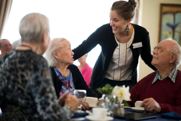 Caretaker talking with residents while they're having a meal at Regency Park Senior Living, Inc.