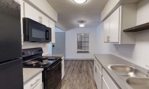 Apartment kitchen with black appliances at The Haylie in Garland, Texas