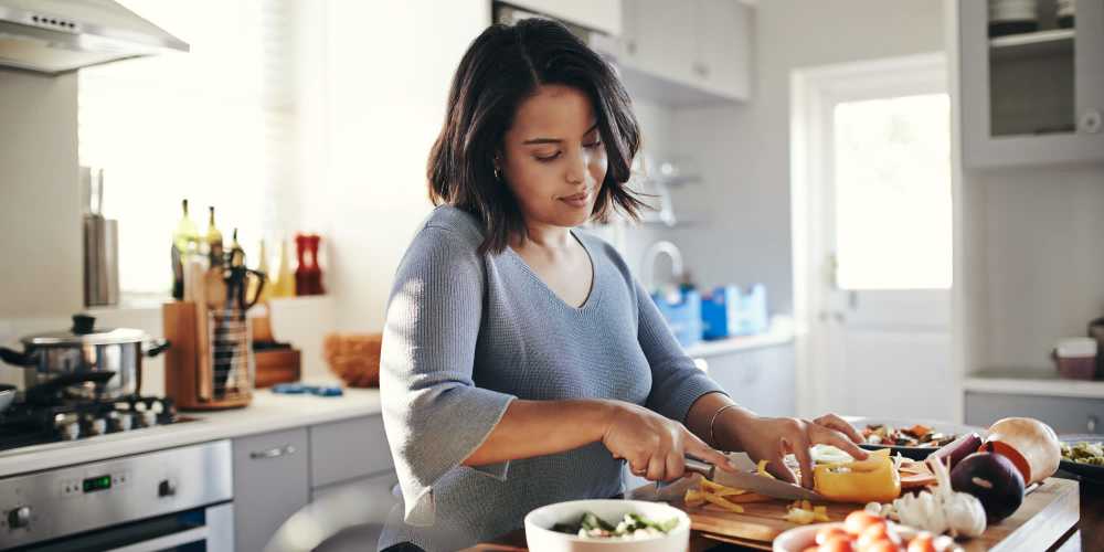 Resident cooking in the kitchen with stainless-steel appliances in a model apartment at Wellshire Apartments in Denver, Colorado