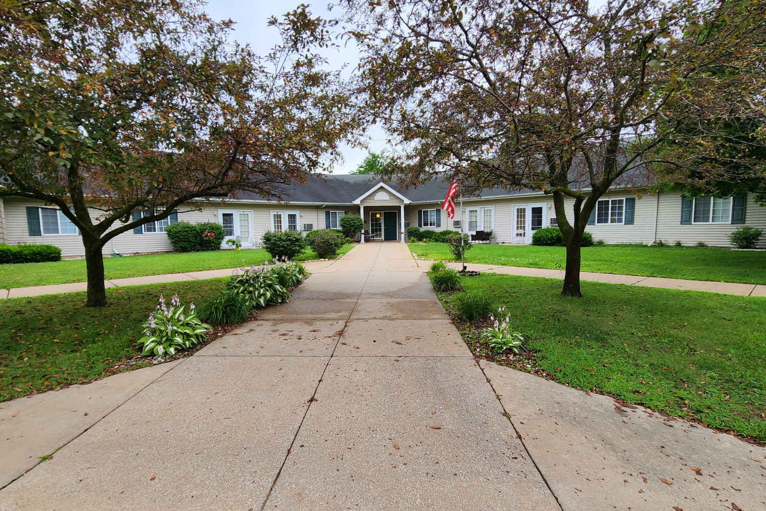 Entrance view of apartment with well maintained lawn and pathway at Woodbrook Apartments in Three Rivers, Michigan