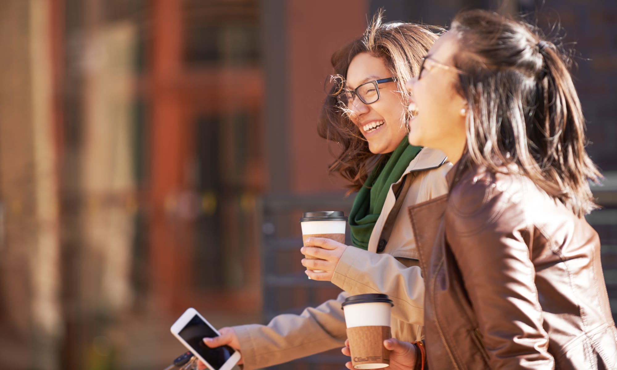 Student friends out enjoying coffee while on a walk in the city near Uptown Ann Arbor in Ann Arbor, Michigan