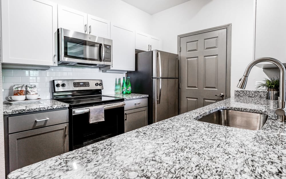 Granite countertops and tile backsplash in model home's kitchen at Beck at Wells Branch in Austin, Texas